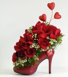 Unique Valentines Day with red high heel shoe as a vase base filled with red roses and small white flowers.JPG