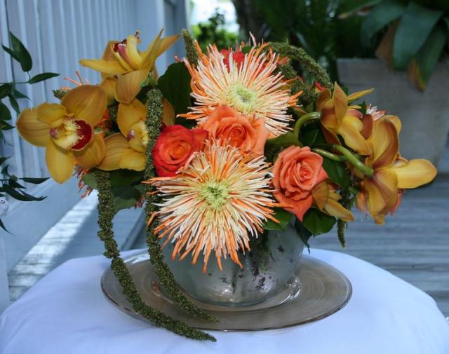 Elegant wedding centerpiece with orange flowers in silver vase