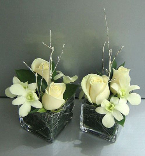 Chic short wedding centerpieces with white flowers and large green leaves