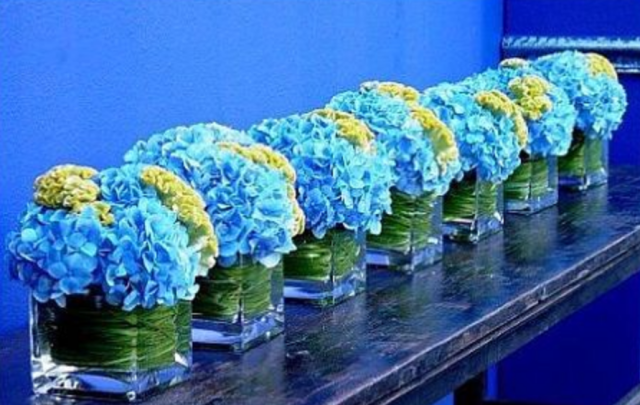 Trendy center piece with blue and yellow flowers with square vases.PNG